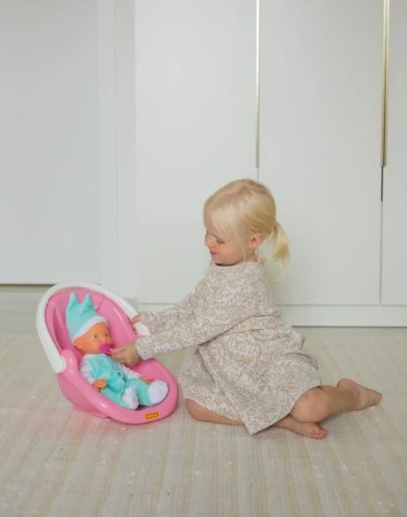 Toddler girl playing with baby doll